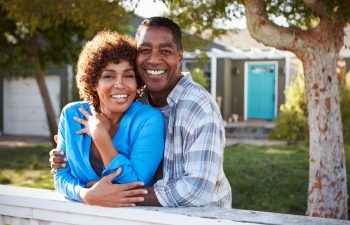 Portrait Of Mature Couple Looking Over Back Yard Fence